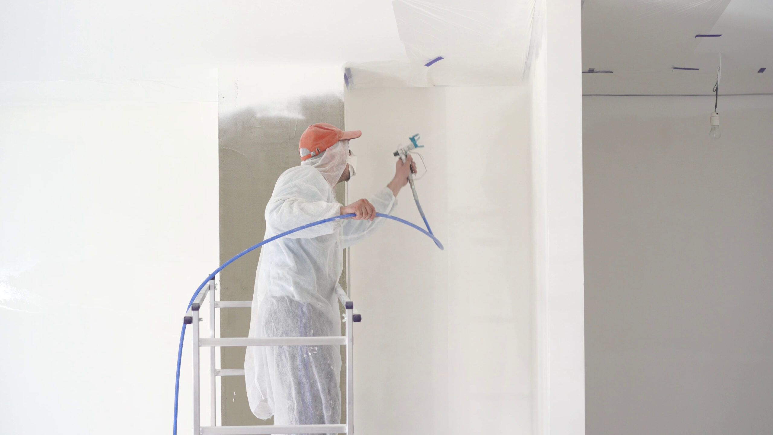 Repair Of The Apartment Professional Painter Paints The Walls With White Paint Spray Gun